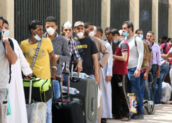 Egyptians queue up outside a school that was turned into a centre to receive residency violators wishing to avail an amnesty Kuwait announced for April, amid the coronavirus COVID-19 pandemic crisis, in Kuwait City on April 6, 2020. (Photo by YASSER AL-ZAYYAT / AFP)